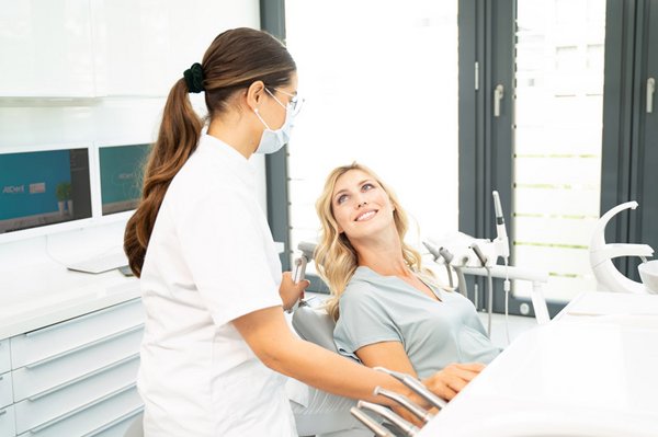 Zahnärztin schaut auf Patientin im Behandlungsstuhl