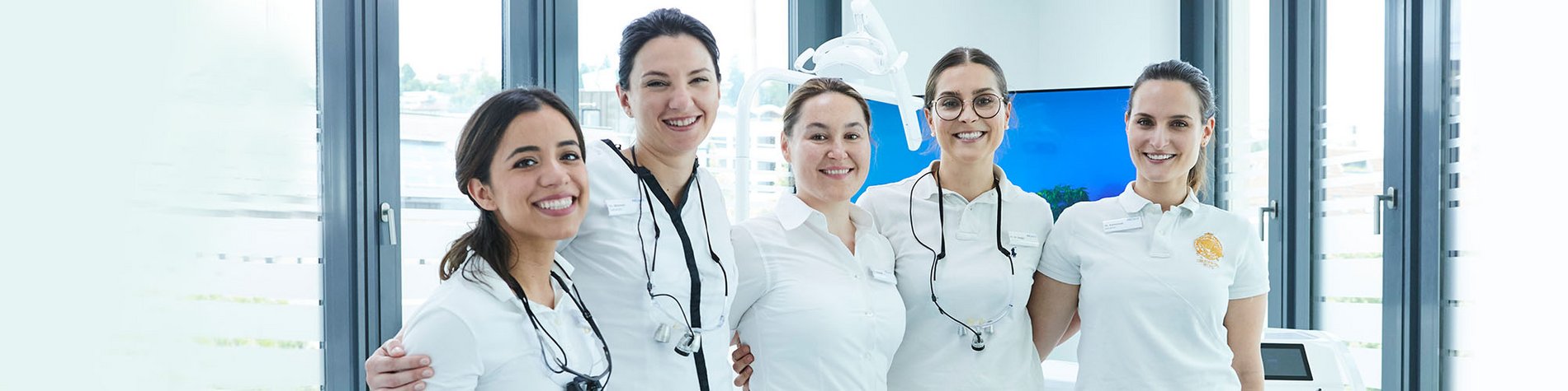 Fünf Zahnärztinnen stehen lächeln nebeneinander